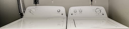 Two white front loading washing machines in a laundry room.