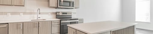 One and two Bedroom Apartment Homes with Large Kitchens with ample storage and light cabinets, quarts countertops and stainless steel appliances at Pinnacle Heights Apartments in Rogers, Arkansas