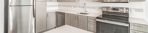 One and two Bedroom Apartment Homes with Large Kitchens with ample storage and light cabinets, quarts countertops and stainless steel appliances at Pinnacle Heights Apartments in Rogers, Arkansas
