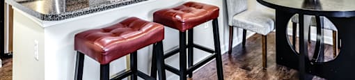 a kitchen with a breakfast bar and stools next to a kitchen counter at The Larimore Apartments, Omaha, NE 68164
