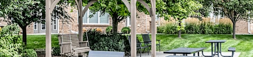 a picnic area with picnic tables and a grill at Legacy Commons Apartments in Omaha, NE