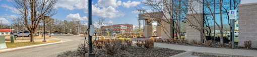 an empty parking lot in front of a building with a tall tower and a street