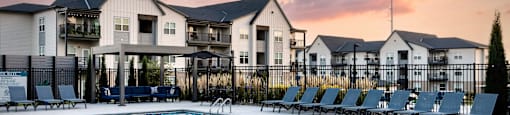 A pool with chairs and a building in the background.