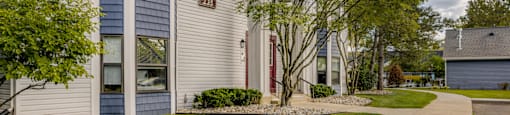 a white building with a sidewalk and trees in front of it