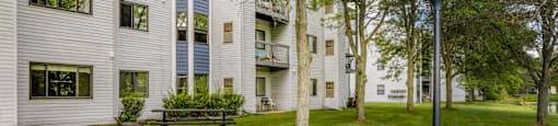 a large white apartment building with a lawn and trees