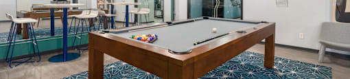 a pool table sits in the middle of a room with a bar in the background
