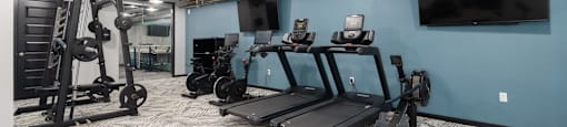 a spacious fitness room with cardio equipment and a flat screen tv