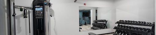 a spacious fitness room with cardio machines and weights