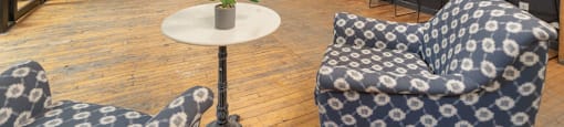 a room with two blue and white chairs and a table with a potted plant