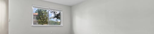Empty room with a window and wooden floor.