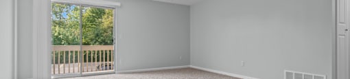 an empty living room with carpet and a door to a balcony