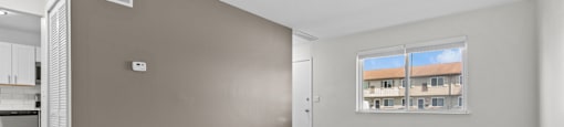 A room with brown walls and wooden flooring with a window.