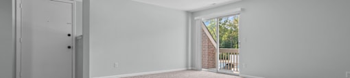 an empty living room with carpet and a door to a balcony