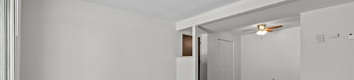 an empty living room with white walls and a ceiling fan