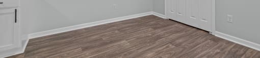 an empty living room with a door to a closet and a kitchen