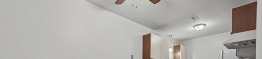 an empty living room with a kitchen in the corner