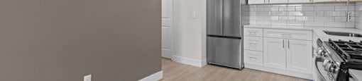 A kitchen with white cabinets and a stainless steel refrigerator.