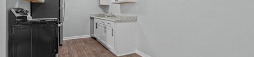 an empty kitchen with white cabinets and a black refrigerator and stove