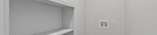 A white shelving unit in a room with wood flooring and a white wall.