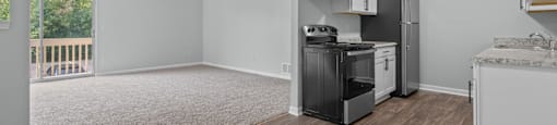 an empty living room with a kitchen with a stove and refrigerator