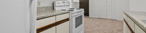 an empty kitchen with white appliances and a ceiling fan