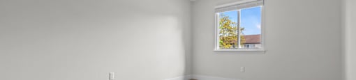 A room with a window and wooden flooring.
