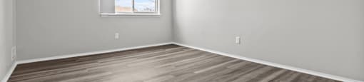 A room with wooden flooring and a window.
