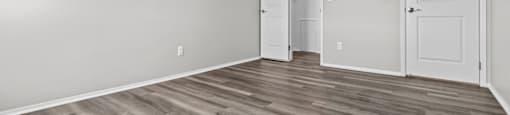 A room with a wooden floor and two white doors.
