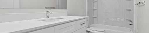 A white bathroom with a toilet, sink, and bathtub.