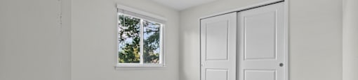 A room with a window and two doors.