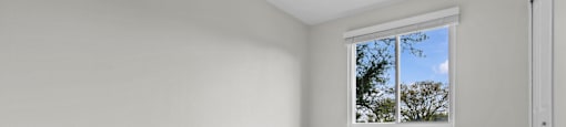 Empty room with a window and wooden flooring.