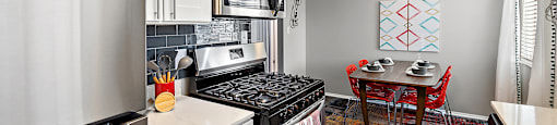 spacious kitchen with stainless steel appliances and white cabinets and a dining room table with chairs