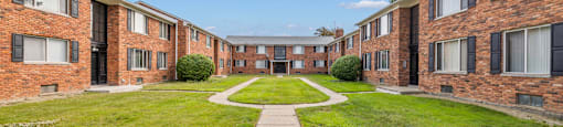 an exterior view of an apartment building with a grass yard and sidewalk