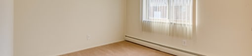 a spacious living room with a large window and carpeting