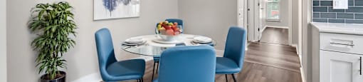 A dining room with a table set for two and a potted plant.
