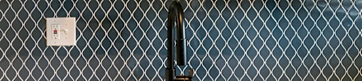 A kitchen sink with a black faucet and a tile backsplash.