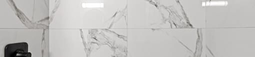 A white marble bathroom with a black faucet.