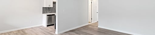 A room with a wood floor and a doorway leading to another room.