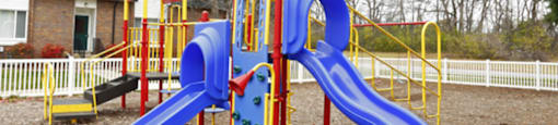 A playground with a blue slide and yellow and red structures.