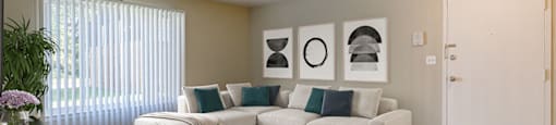 A living room with a white couch, a black coffee table, and a plant on the left side.