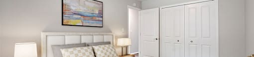 A bedroom with a large bed and a painting above it.
