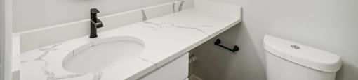A bathroom with a white sink and toilet.