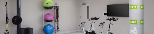 a workout room in a gym with weights and a tv