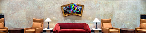 A room with a red couch and chairs with a painting hanging on the wall.