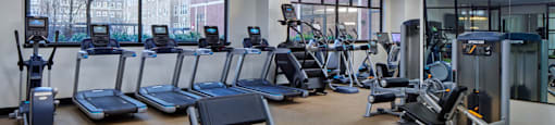 A gym with a variety of equipment including treadmills, stationary bikes, and weight machines.