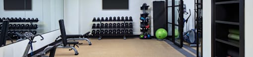 A gym with exercise equipment and a green mat on the floor.