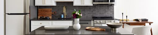 a kitchen with white cabinets and a black counter top