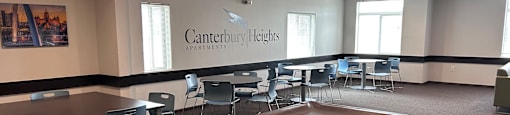 A billiard table in the middle of a room with chairs and a sign that says Canterbury Heights Apartments.