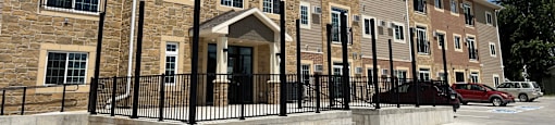 a three story apartment building with cars parked outside