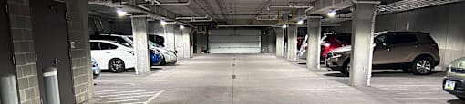 A long, empty parking garage with cars parked on both sides.